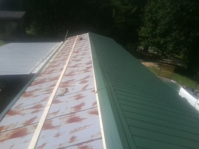 Old rusted panels beside newly installed green metal roofing — Wind Damage Roof Repair by Roofing Brothers in East Hickory