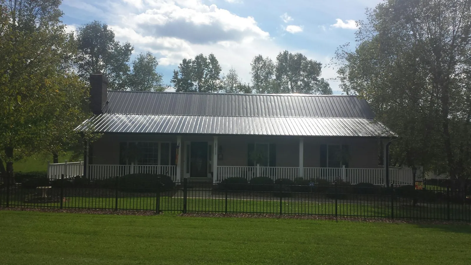 Gray metal roof on a brick ranch with a full width front porch — Gutter Guard Installation work by our crew in East Hickory