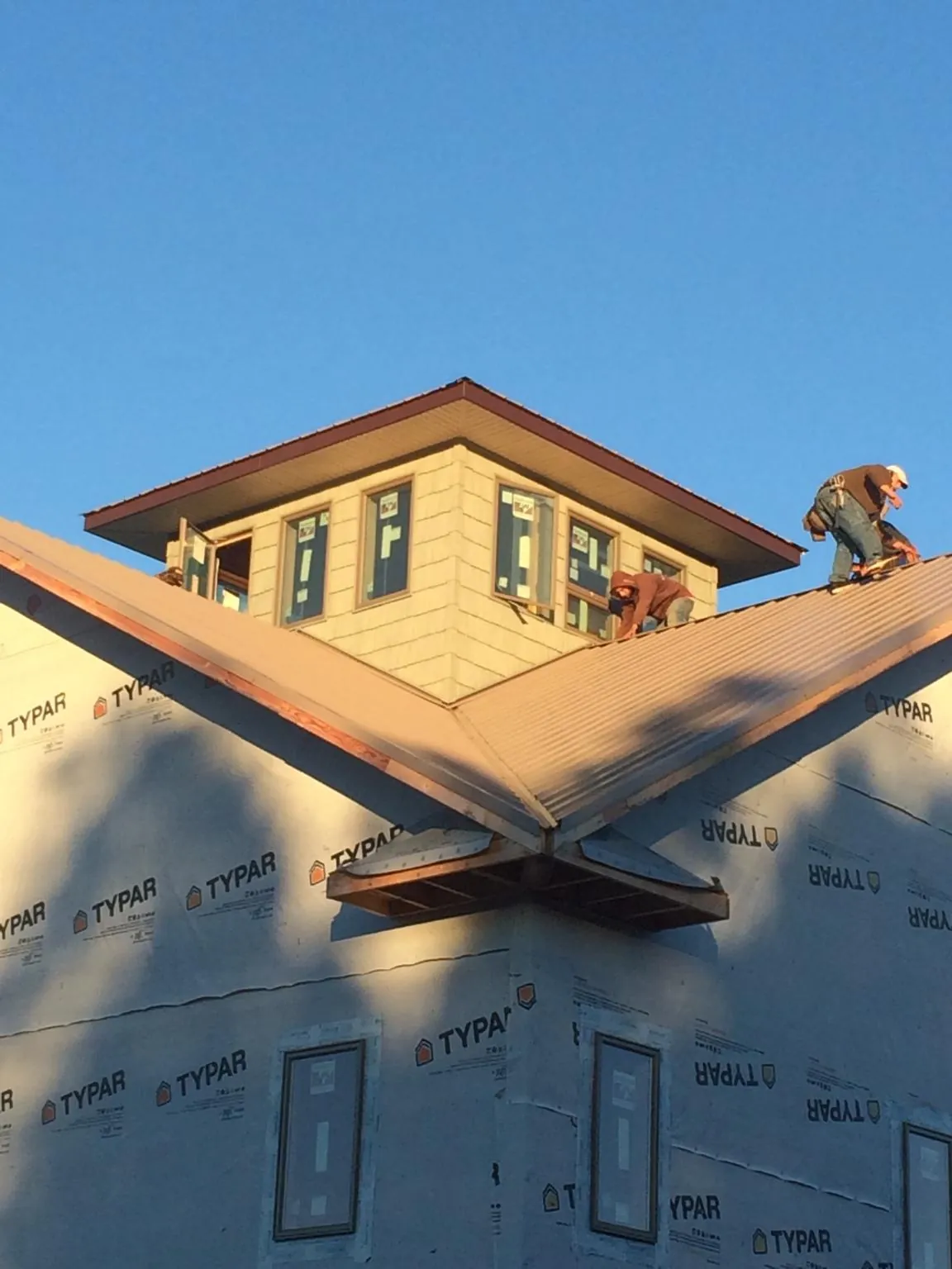 Roofers working around a rooftop cupola on a new metal roof at sunset — Roof Waterproofing in East Hickory by Roofing Brothers